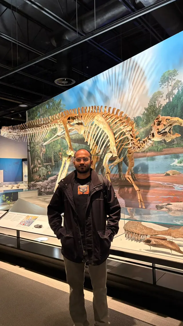 Karthik in front of a dinosaur skeleton exhibit at the Royal Alberta Museum